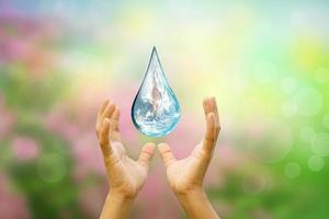 World Water Day Hands waiting for the world in water drop shape on background blurred flowers and sky with the light of the sun. Elements of this image furnished by NASA. photo