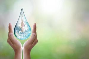 World Water Day Hands waiting for the world in water drop shape on background blurred flowers and sky with the light of the sun. Elements of this image furnished by NASA. photo