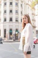 Asian woman with bronze hair  in white shirt while walks on street. photo