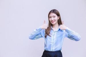 Beautiful business woman who has long hair Asian with a blue shirt smiles and shows thumb up to present something on a white background. photo