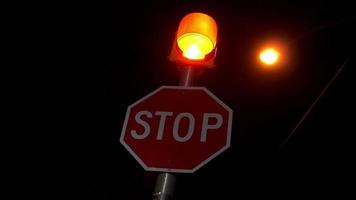 stoppschild rotes licht blinkt auf dunkler ländlicher landschaftskreuzung video