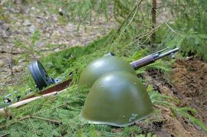 a wartime helmet and a machine gun lie on the edge of the trench photo