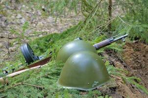 un casco de guerra y una ametralladora yacen al borde de la trinchera foto