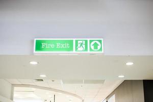 Source text White background fire exit sign White lettering is clearly positioned in a mall for customers to see in the event of an emergency or fire. Selective focus. Blurred background. photo