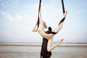 exercises with aerial silk outdoor, sky background. beautiful fit woman training acrobatic in airt. photo