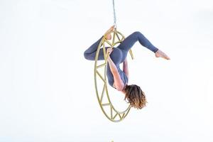 Woman hanging in aerial silk in white studio photo