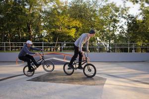 grupo de jóvenes con bicicletas bmx en skate plaza, ciclistas acrobáticos en skatepark foto