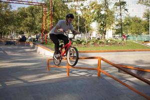 Bmx rider entrenando y haciendo trucos en street plaza, bicyxle stunt rider en cocncrete skatepark foto