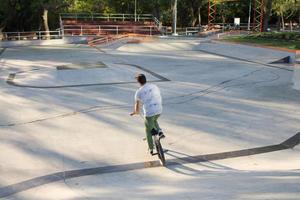 Bmx rider entrenando y haciendo trucos en street plaza, bicyxle stunt rider en cocncrete skatepark foto