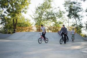 grupo de jóvenes con bicicletas bmx en skate plaza, ciclistas acrobáticos en skatepark foto