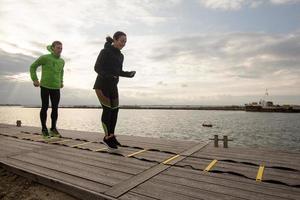 group of young people training outdoors, runners exercises, sea or river background photo