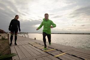 group of young people training outdoors, runners exercises, sea or river background photo