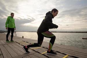 group of young people training outdoors, runners exercises, sea or river background photo