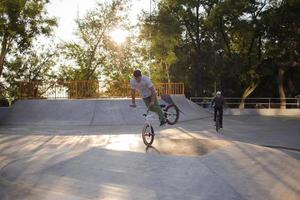 Group of young people with bmx bikes in skate plaza, stunt bicycle riders in skatepark