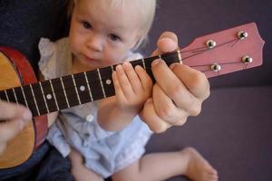 padre barbudo con niños juegan en ukelele interior foto