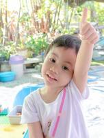 niña asiática con adorable pelo corto mostrando los pulgares hacia arriba. foto