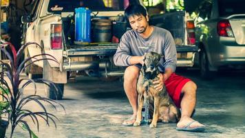 Asian man sits with a dog in his home photo