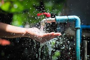 Water concept in everyday life. Hands supporting the water flowing from the faucet. water splashing from the tap photo