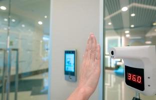 Selective focus on non-contact temperature assessment device. People check body temperature by infrared digital thermometer for screening fever of coronavirus. Palm scan at infrared thermometer. photo