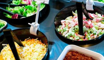 Salad bar buffet at restaurant. Fresh salad bar buffet for lunch or dinner. Healthy food. Celery and crab stick sliced in black bowl on counter. Catering food. Banquet service. Vegetarian food. photo
