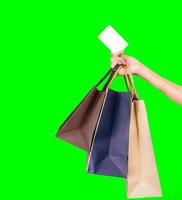 mujer consumidora mano sosteniendo una colorida bolsa de compras y tarjeta de crédito aislada en un fondo verde. concepto de consumismo. mujer asiática comprando y pagando con tarjeta de crédito. concepto de venta de viernes negro. foto