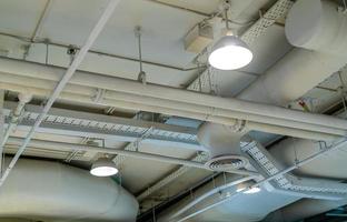 Air duct, wiring and plumbing in the mall. Air conditioner pipe, wiring pipe, and plumbing pipe system. Building interior concept. Ceiling lamp light with opened light. Interior architecture concept. photo