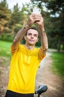 un joven tomándose un selfie con su bicicleta. foto