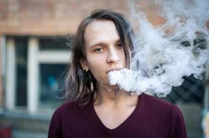 Portrait of a young man in the smoke of cigarettes photo