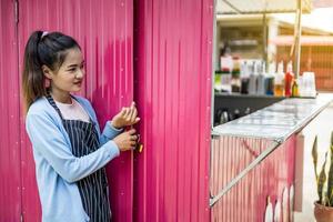 mujer sonriente, seductora y encantadora cerca de la puerta de zinc rosa. foto