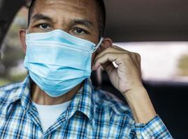 Close-up of a man wearing a double-layered blue mask inside the car. photo