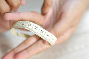 Female hand measuring finger with a tape measure photo