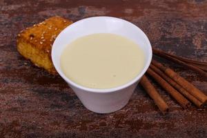 Condenced milk in the bowl with sinnamon and pastry photo