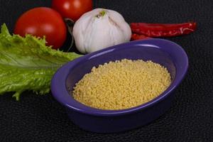 Raw couscous in the bowl served salad leaves, tomato and pepper photo