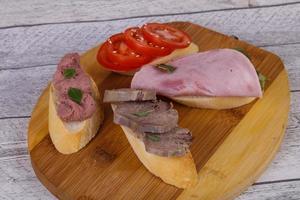 Bruschetta with tomato, ham and tongue photo