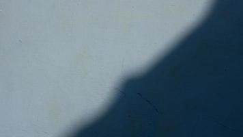 el sol se proyecta sobre el muro de hormigón azul, la sombra de la sombrilla. primer plano de la sombra en la pared foto