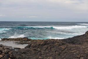 Turbulent ocean waves with white foam beat coastal stones photo