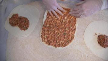 The cook is preparing the pita for baking. The cook pours the stuffing of the pita into the dough and prepares it for baking.