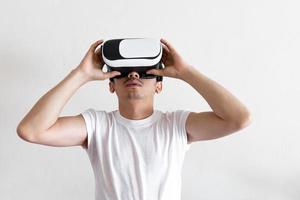 Young man wearing virtual reality goggles headset on gray background. Concept of VR, video game, future, gadgets and technology. photo