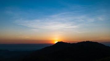 Silhouette of mountains during sunrise with sky and clouds. Beautiful natural landscape in the summertime photo