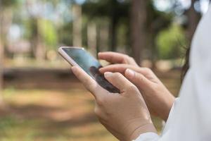 primer plano de la mano de la mujer de la imagen usando el teléfono móvil en el parque. búsqueda o concepto de redes sociales. foto