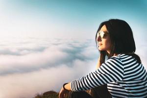 Attractive brunette caucasian close up face looking to the left  with blurry clouds in the background photo