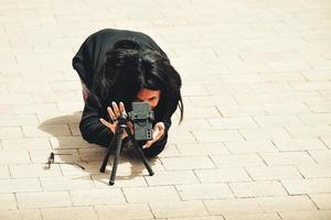 Excited young brunette caucasian woman travel photographer shoot with smartphone on tripod outdoors in public in tourist destination photo