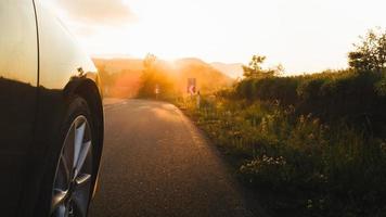 Cinematic low angle view tire on asphalt road drive in motion with sunset and smoke in background. Road trip concept outdoors
