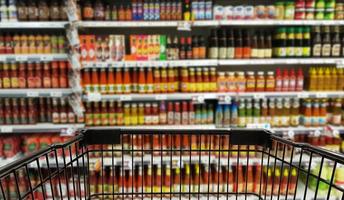 Abstract blurred image of condiments department with trolley, selective focused at shopping cart.