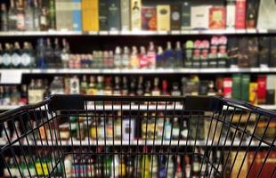 Abstract blurred image of alcohol store with trolley, selective focused at shopping cart. photo