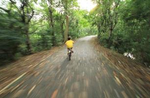 movimiento burred de niño montando bicicleta a través del bosque foto