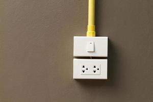 Electric light switch and socket on the empty wall photo