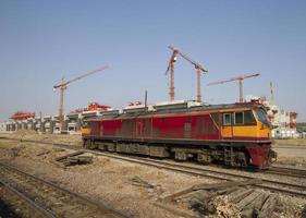 Locomotora antigua en vía férrea con sitio en construcción en segundo plano. foto