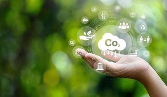 CO2 emission reduction concept in hand with environmental icons, global warming, sustainable development, connectivity and renewable energy green business background. photo