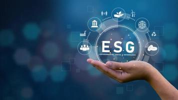 conceptos de esg sobre medio ambiente, sociedad y gobernanza en la palma de la tecnología con icono sobre fondo azul entorno social esg presione un botón en la pantalla. foto